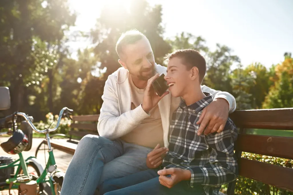 Dad holding phone to boys ear so he can speak with Life Improvements about his NDIS referral