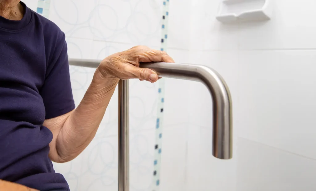 Woman holding onto newly installed hand rail in bathroom