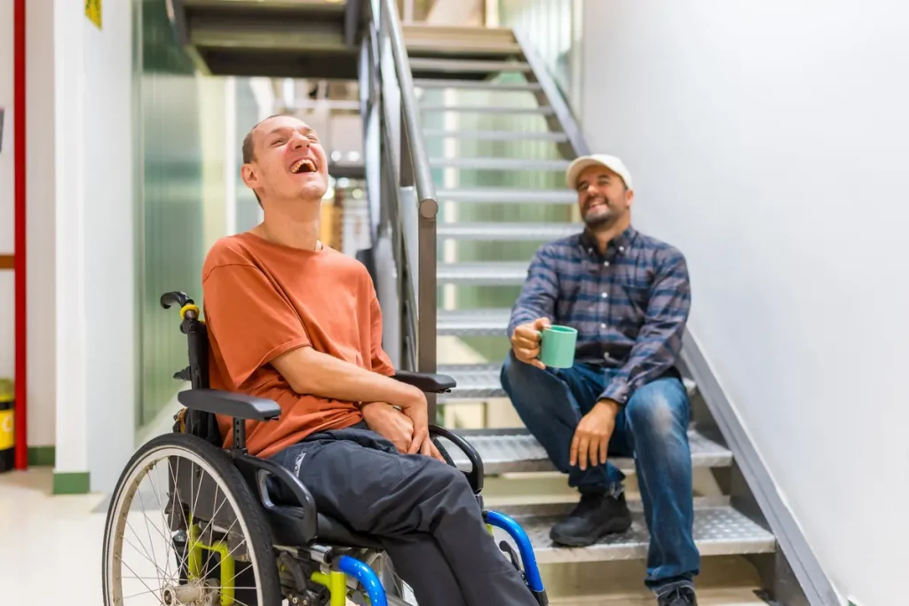 Disabled male and support worker enjoying conversation and laughing