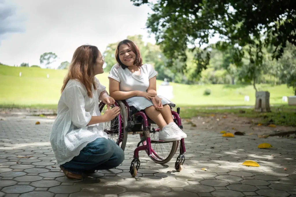 Disabled woman in wheelchair enjoying conversation with her support worker